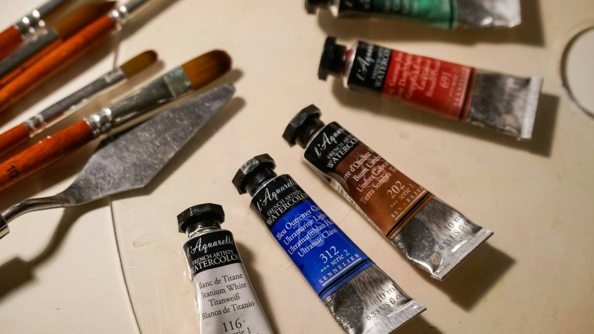 art supply beginner painting how do – photo showing organized beginner painting kit with acrylics, three brushes, palette, water cup, and canvas paper